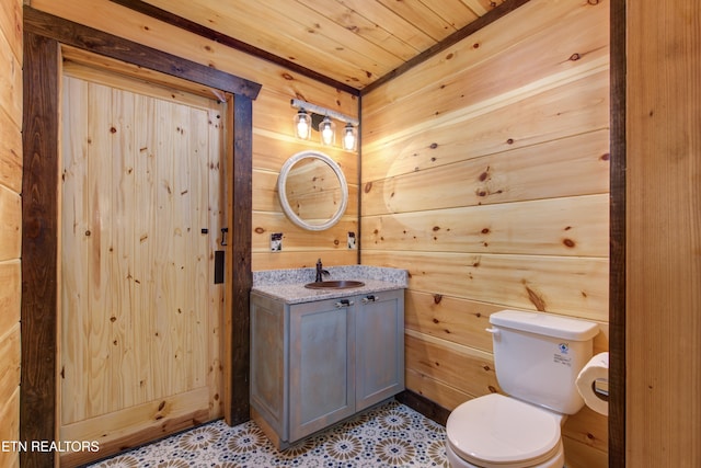 half bath featuring wooden ceiling, toilet, wooden walls, vanity, and tile patterned floors