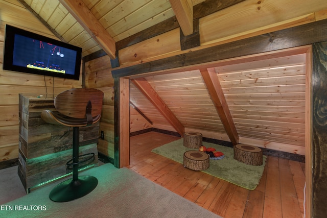 unfurnished room with lofted ceiling with beams, wood walls, wood-type flooring, and wood ceiling