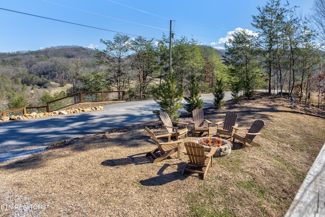 view of yard with driveway, a fire pit, a mountain view, and a wooded view