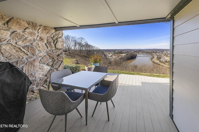 wooden terrace with outdoor dining space, a water view, and area for grilling