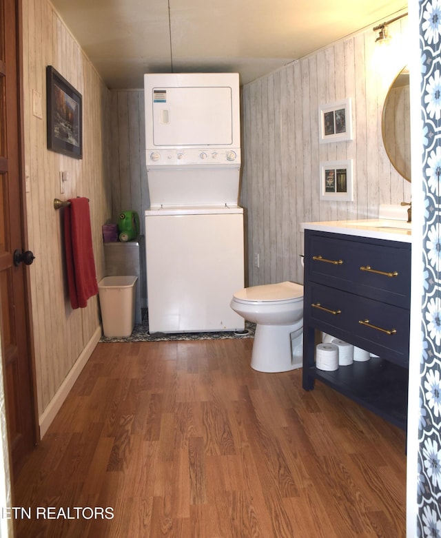 bathroom with stacked washer and clothes dryer, vanity, toilet, and wood finished floors