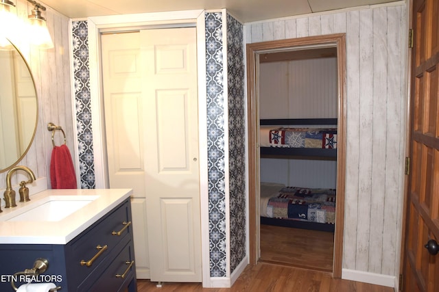 bathroom featuring baseboards, vanity, ensuite bath, and wood finished floors