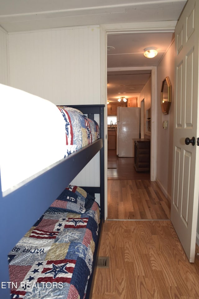 bedroom featuring visible vents, wood finished floors, and freestanding refrigerator