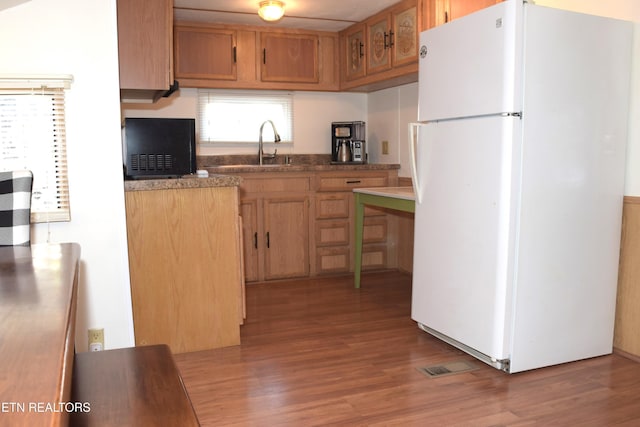 kitchen featuring freestanding refrigerator, visible vents, a sink, and wood finished floors