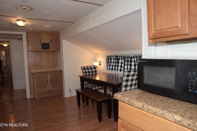 dining space with visible vents, vaulted ceiling, and wood finished floors