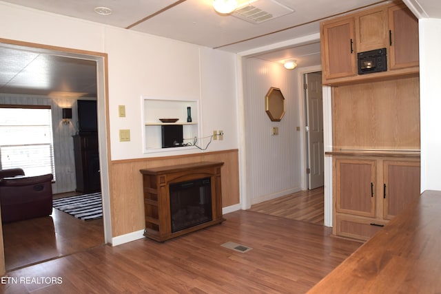 unfurnished living room featuring wood finished floors, a glass covered fireplace, and visible vents