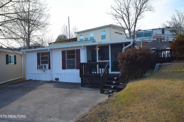 manufactured / mobile home with metal roof, a front lawn, cooling unit, and a sunroom