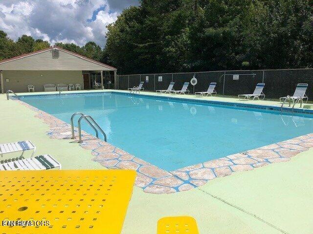 community pool with a patio area and fence