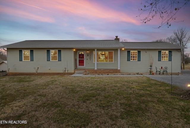 single story home with metal roof, a chimney, and a front lawn