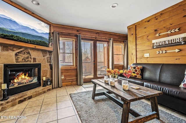 living area featuring a stone fireplace and light tile patterned flooring