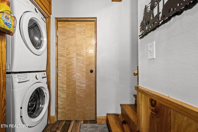 washroom with laundry area, a textured wall, stacked washer / dryer, and wood finished floors