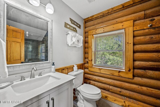 full bath featuring toilet, vanity, wainscoting, log walls, and a shower with door