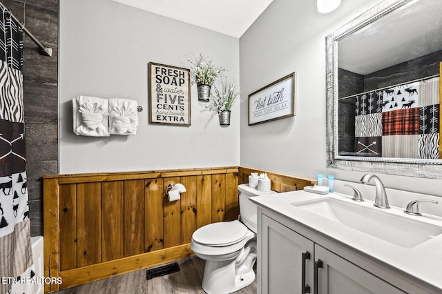 full bathroom with a wainscoted wall, visible vents, toilet, a shower with shower curtain, and vanity