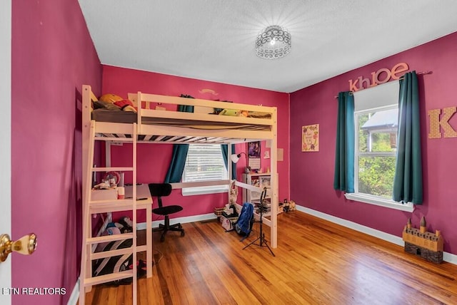 bedroom with wood-type flooring and baseboards