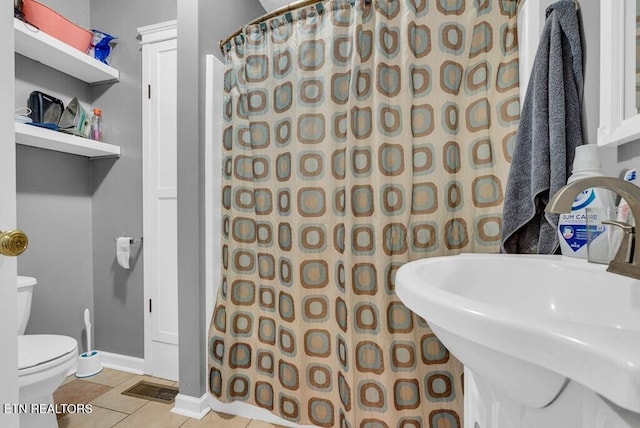 bathroom with toilet, a shower with shower curtain, a sink, baseboards, and tile patterned floors