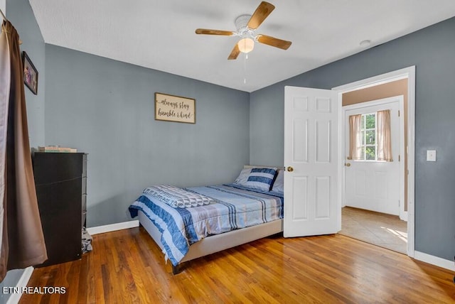 bedroom with a ceiling fan, baseboards, and wood finished floors