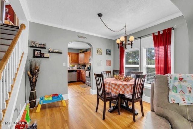 dining space featuring arched walkways, ornamental molding, stairway, and light wood-style floors