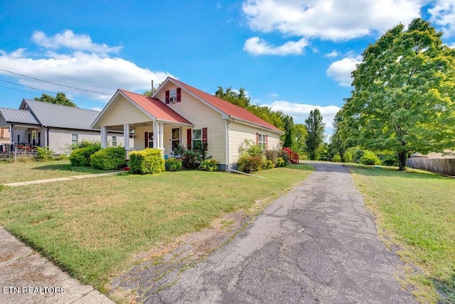 bungalow featuring covered porch, metal roof, a front yard, and fence