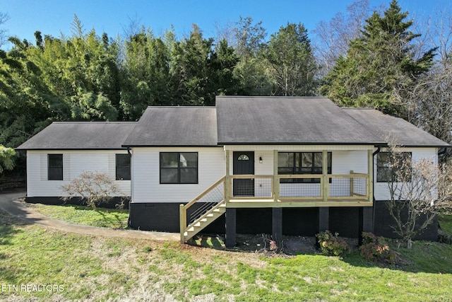 rear view of house featuring stairs and a lawn