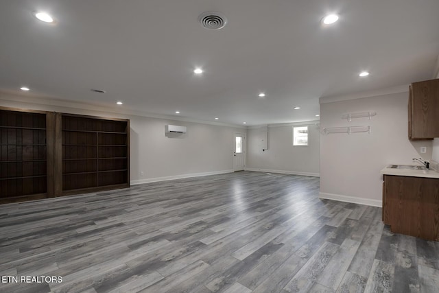 interior space with visible vents, an AC wall unit, a sink, wood finished floors, and crown molding