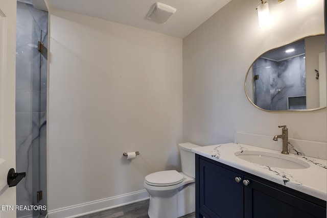 full bath with baseboards, walk in shower, toilet, wood finished floors, and vanity