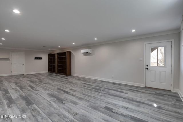 interior space featuring crown molding, baseboards, an AC wall unit, recessed lighting, and wood finished floors