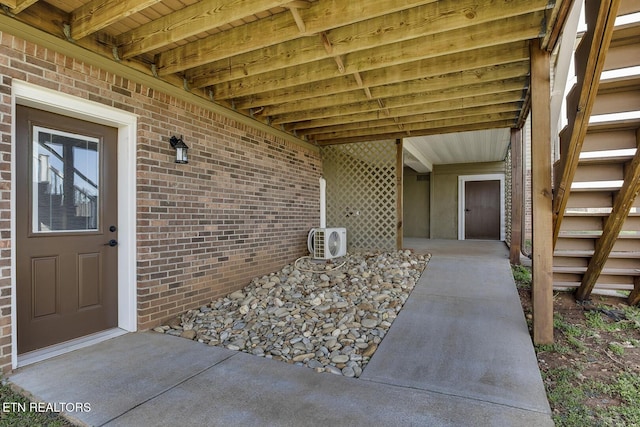 view of exterior entry with brick siding and ac unit