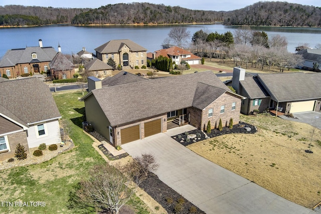 drone / aerial view with a view of trees, a residential view, and a water view