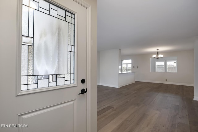 entryway featuring baseboards, a notable chandelier, and wood finished floors