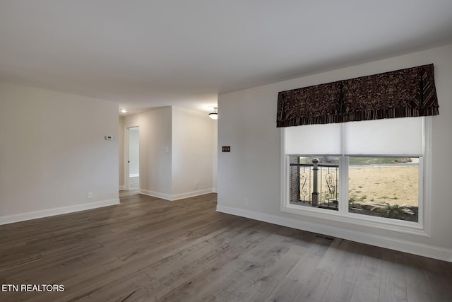 spare room with visible vents, baseboards, and wood finished floors