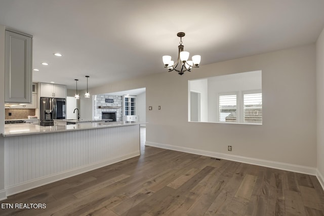 kitchen featuring dark wood-type flooring, a peninsula, stainless steel fridge with ice dispenser, and light countertops