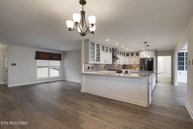 kitchen with dark wood-type flooring, stainless steel fridge, glass insert cabinets, open floor plan, and backsplash