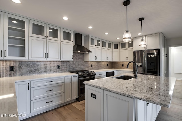 kitchen featuring wall chimney range hood, stainless steel fridge with ice dispenser, double oven range, decorative backsplash, and a sink