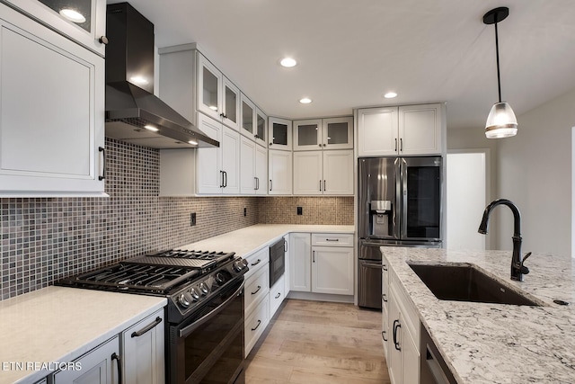 kitchen featuring a sink, backsplash, appliances with stainless steel finishes, and wall chimney exhaust hood