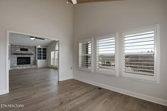 unfurnished living room featuring wood finished floors, a fireplace, baseboards, and ceiling fan