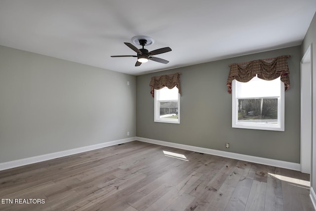 spare room with a ceiling fan, wood finished floors, and baseboards