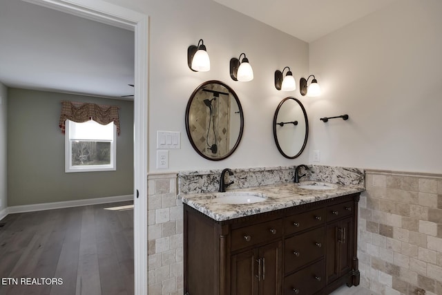 full bathroom with a sink, a wainscoted wall, and tile walls