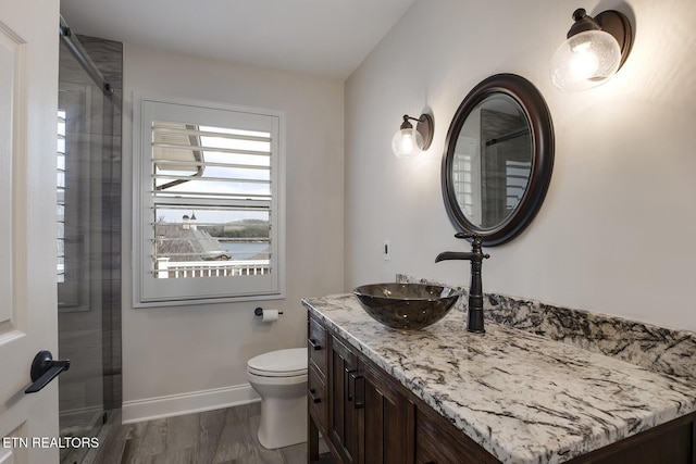 bathroom with baseboards, toilet, walk in shower, and vanity