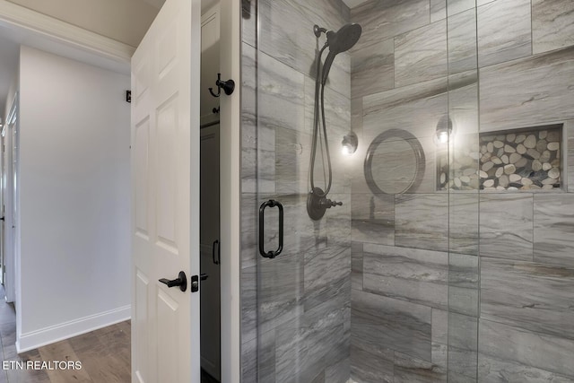 full bath featuring a shower stall, wood finished floors, and baseboards