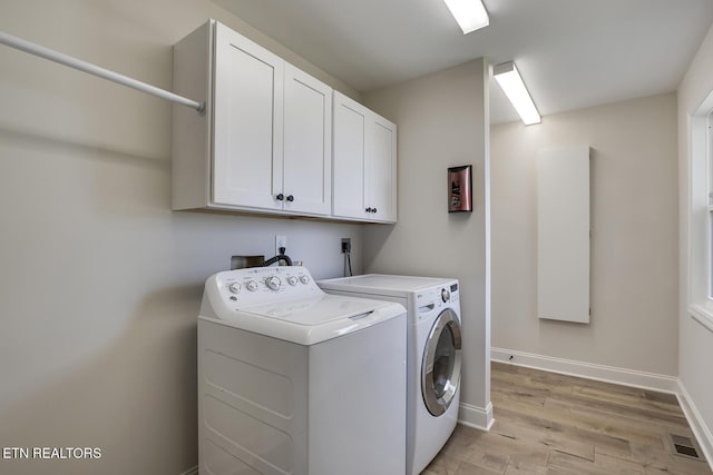 washroom with light wood-type flooring, visible vents, washer and clothes dryer, cabinet space, and baseboards