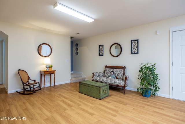 sitting room with light wood finished floors, stairway, and baseboards