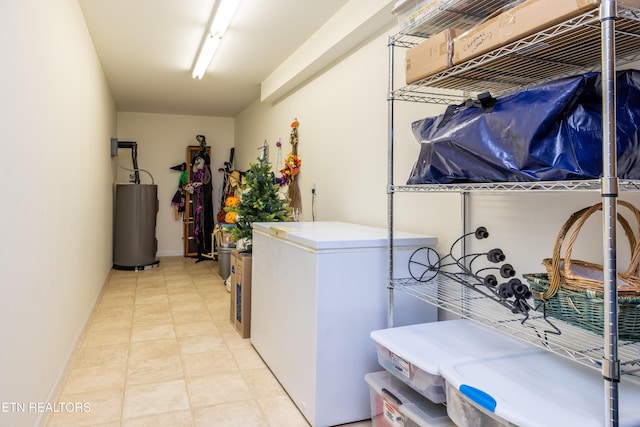 laundry area with water heater, baseboards, and light tile patterned flooring