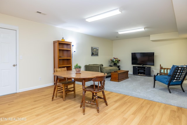 dining room with light wood-type flooring, visible vents, and baseboards