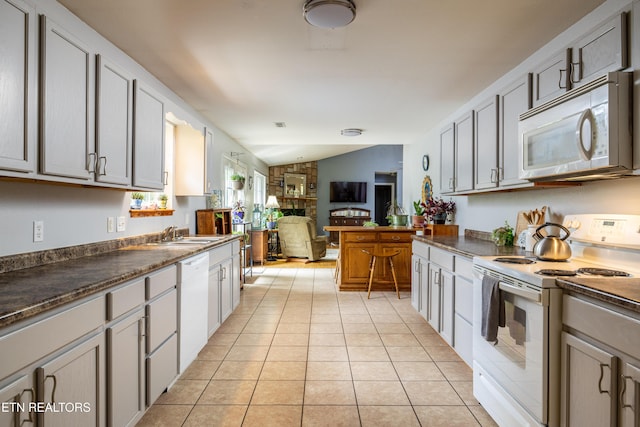 kitchen featuring white appliances, dark countertops, and light tile patterned flooring