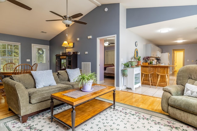 living room featuring light wood-style floors, visible vents, ceiling fan, and high vaulted ceiling