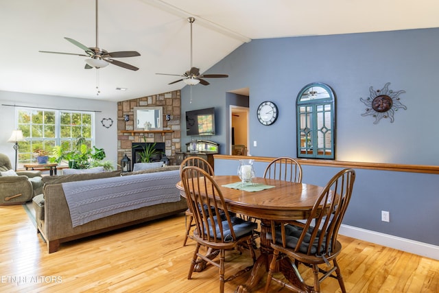 dining area with lofted ceiling, a fireplace, baseboards, and light wood-style floors