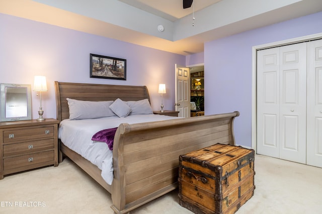 bedroom featuring light carpet, ceiling fan, and a closet