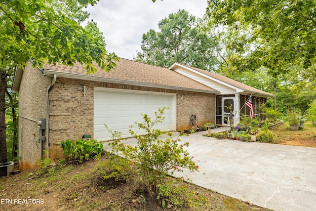 ranch-style home featuring a shingled roof, concrete driveway, brick siding, and an attached garage