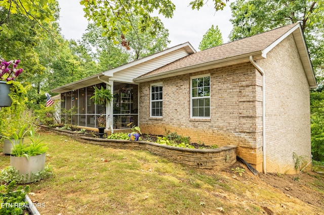 back of house featuring a yard, brick siding, and a sunroom