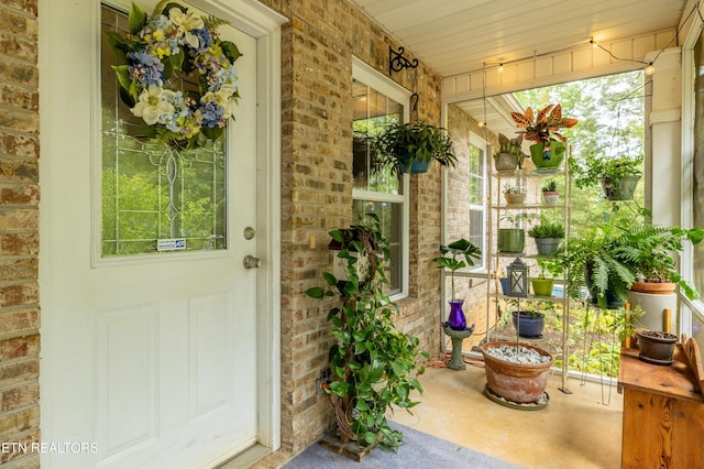 entrance to property featuring a porch and brick siding